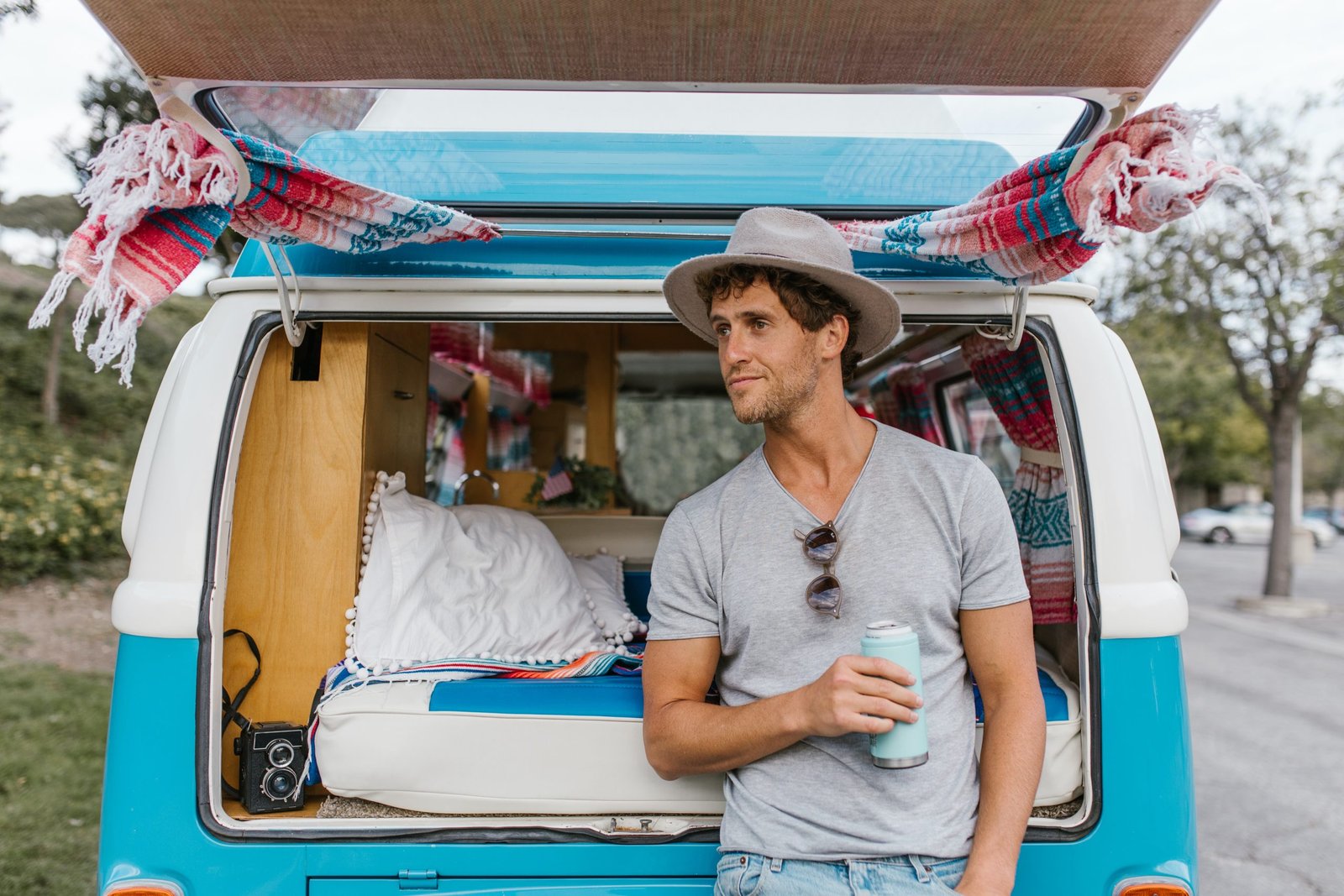 man leans on a blue converted campervan in the sunshine